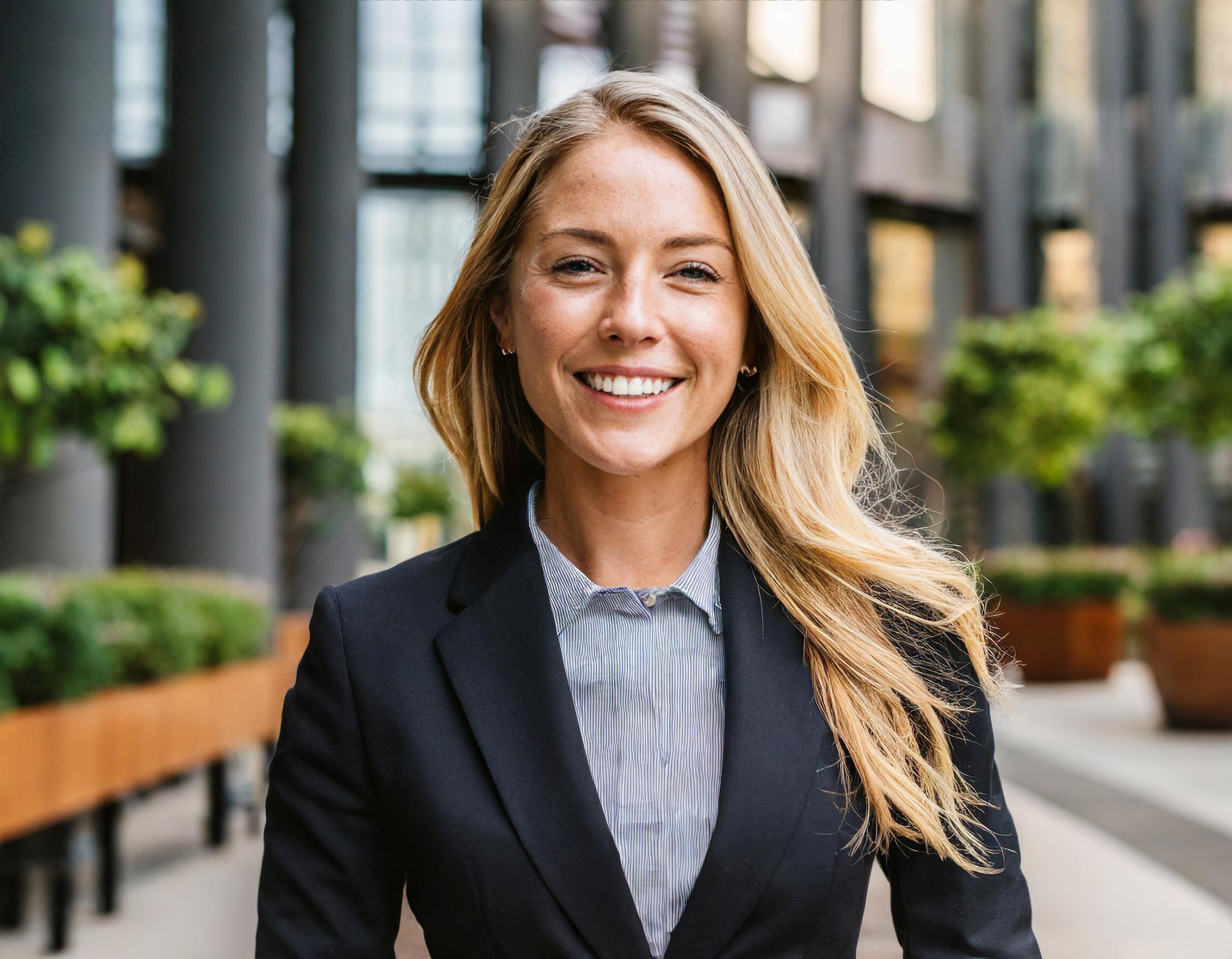 Frau in einem professionellen Umfeld, selbstbewusst lächelnd